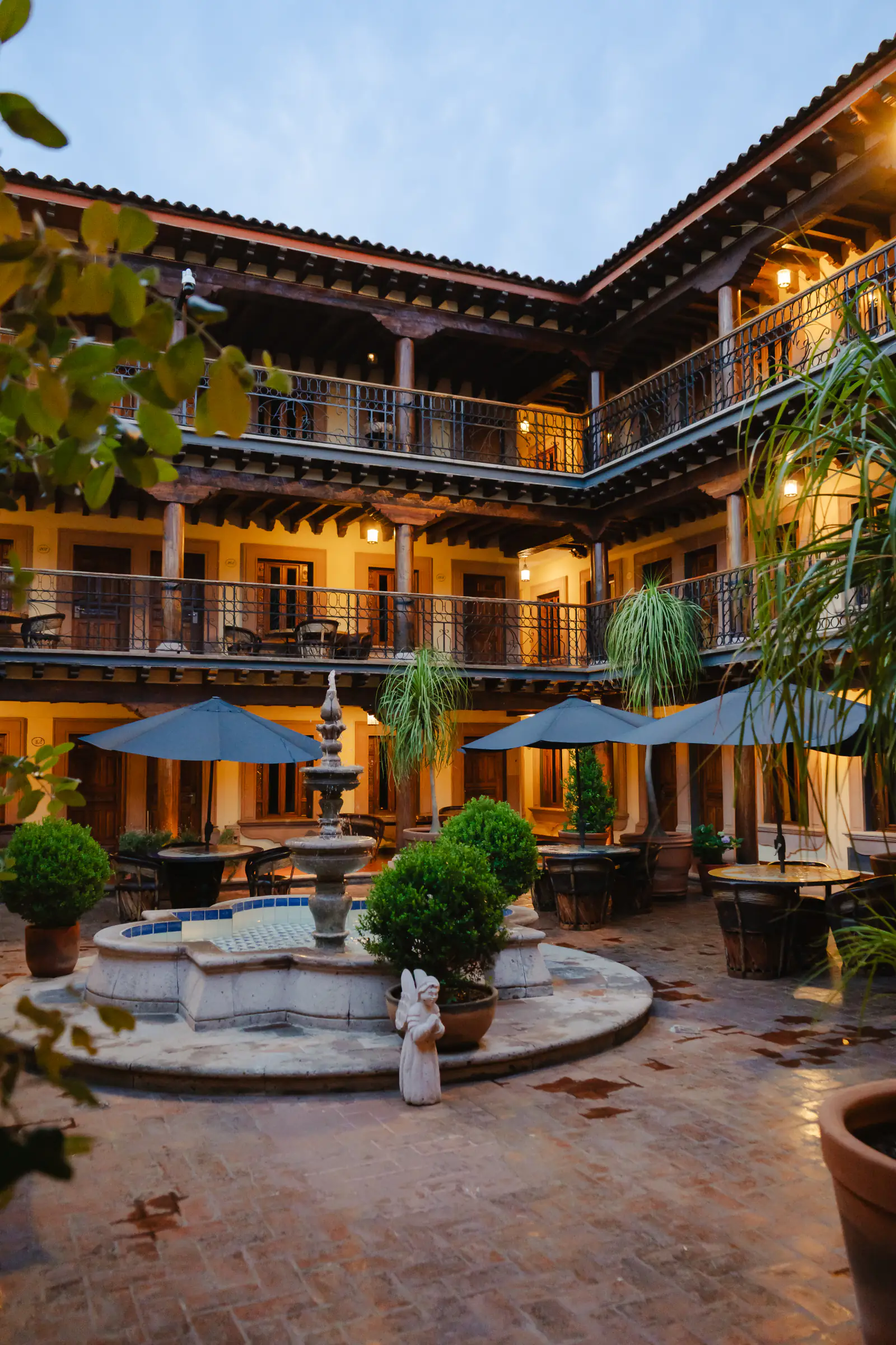 Patio colonial de tres niveles con fuente de cantera al anochecer