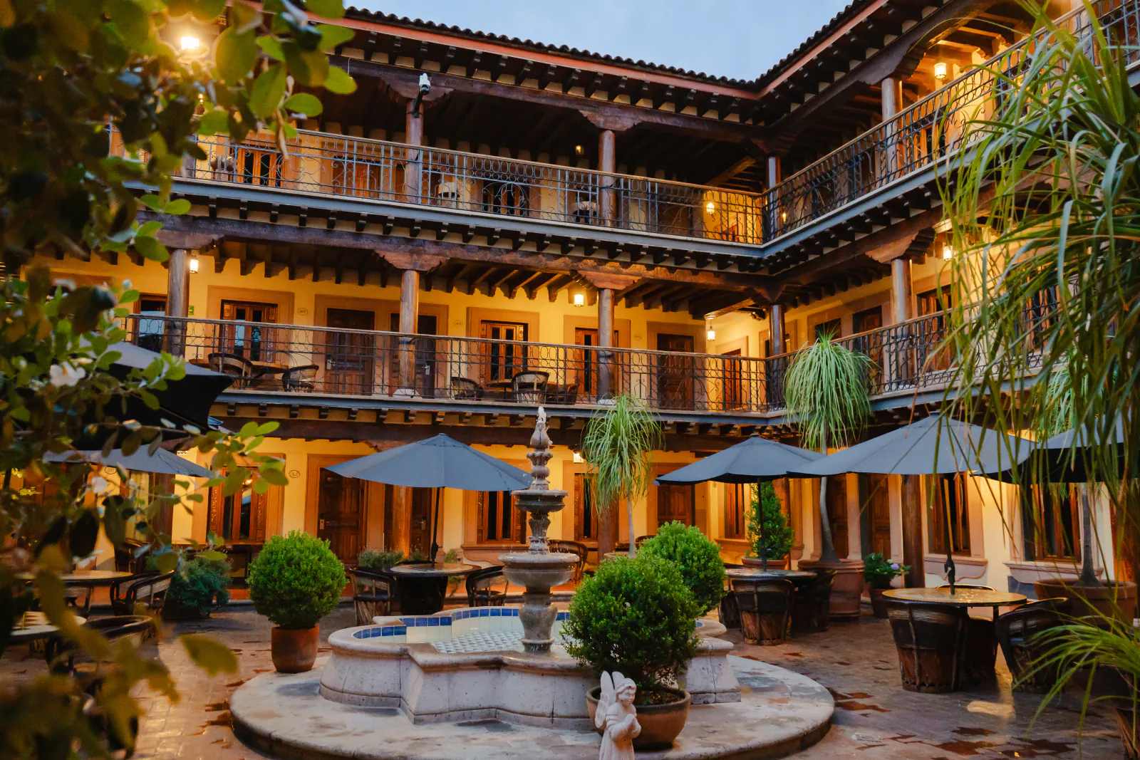 Patio con sombrillas y fuente de talavera al atardecer